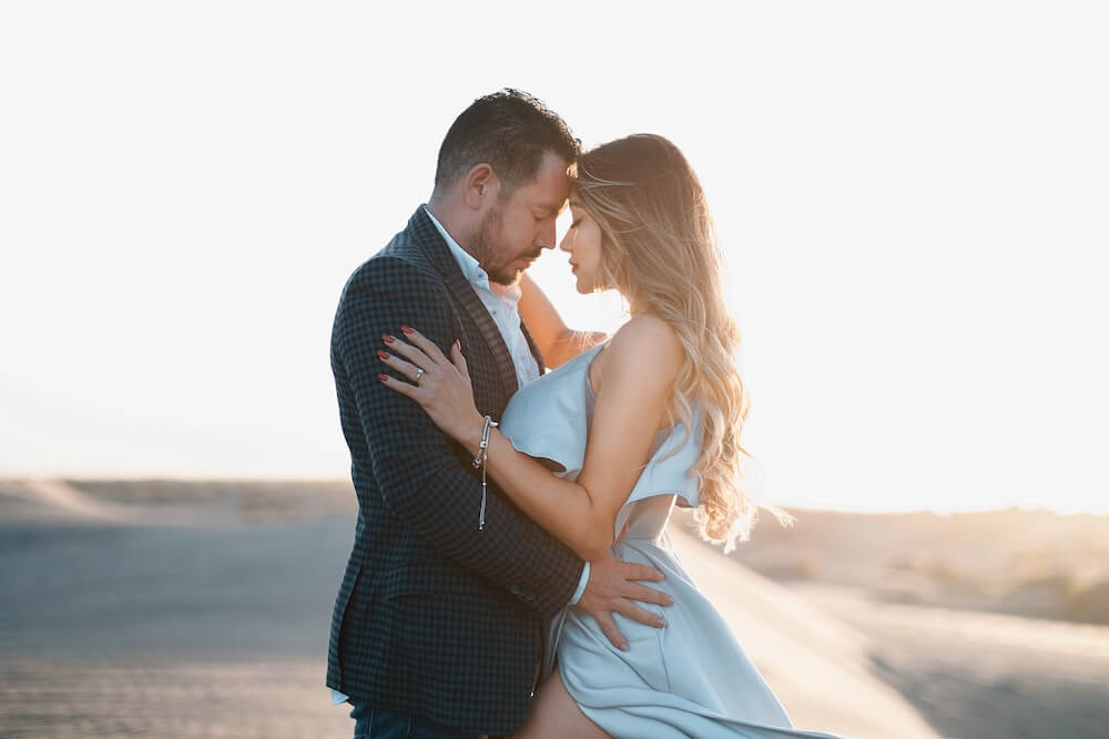 Couple creating a cherished memory during their proposal package, walking hand in hand across the captivating sand dunes.